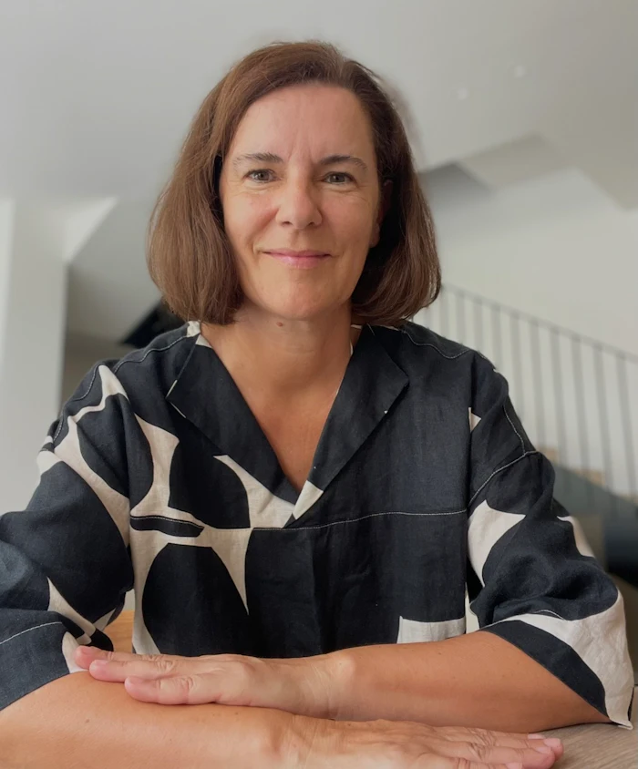 Professional portrait of a woman with shoulder-length brown hair wearing a black and white patterned shirt