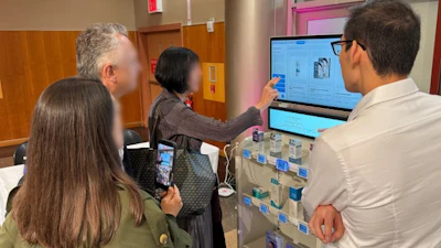 Four people gathered around a digital display during a collaborative work session in an office environment
